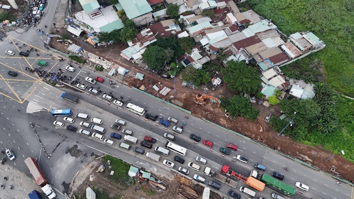 Aerial perspective of a busy road with heavy traffic and urban housing in Ho Chi Minh City, Vietnam.