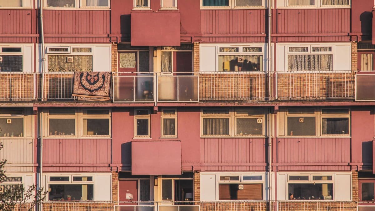 A detailed view of a multi-story apartment building facade with balconies and windows.