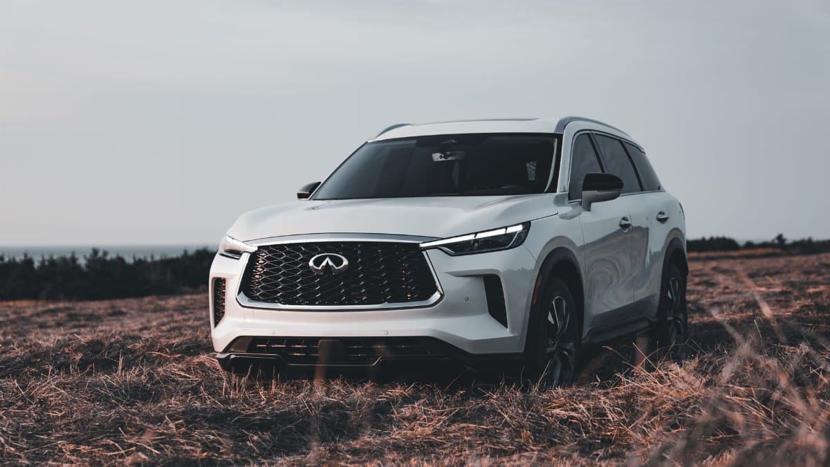 White modern SUV parked on a dry field under a cloudy sky, representing automotive design and adventure.