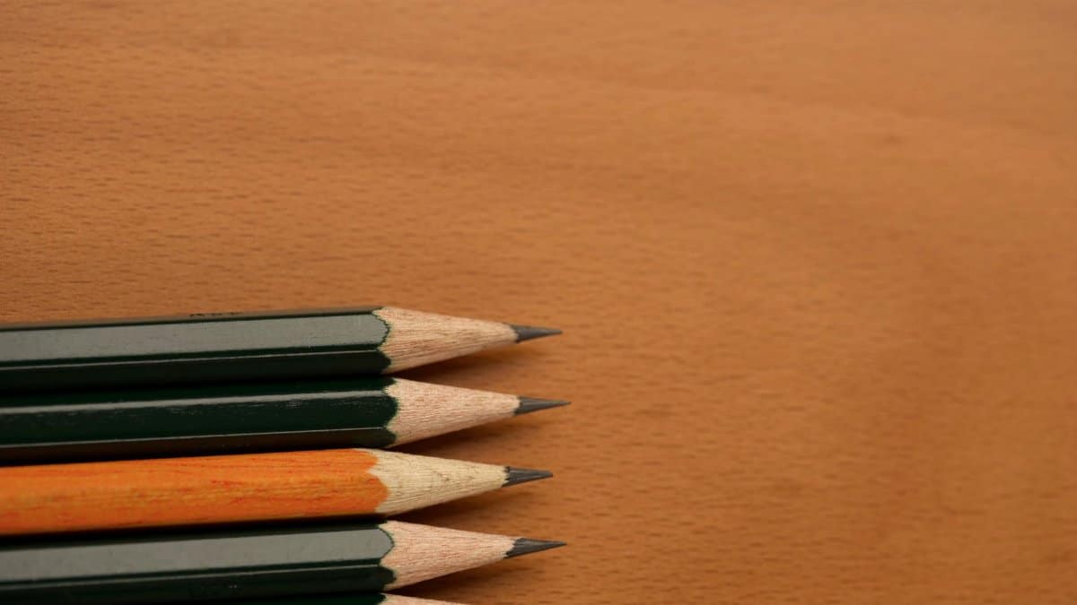 Sharpened pencils aligned on a wooden surface with visible lead tips.