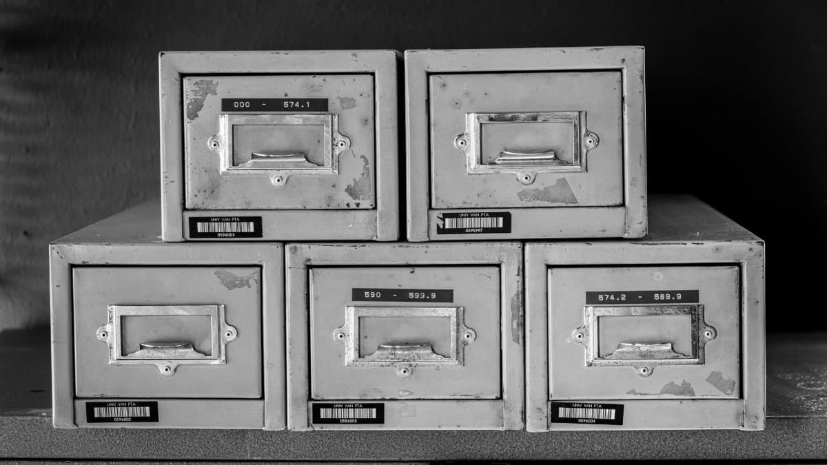 A set of five vintage metal file cabinets, aged and worn, displayed in black and white.