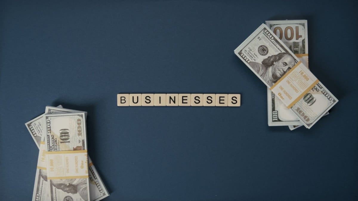 Top view of dollar bills and 'businesses' letter tiles symbolizing financial success.