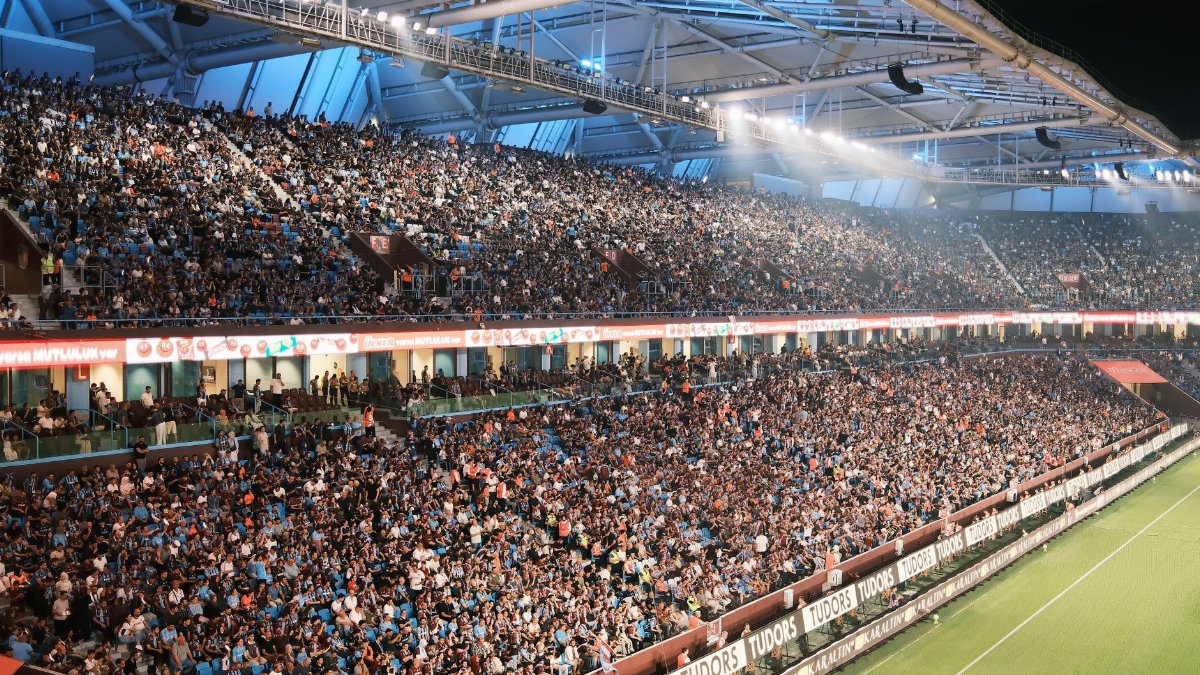 Crowd fills a vibrant soccer stadium at night with bright lights and a lively atmosphere.