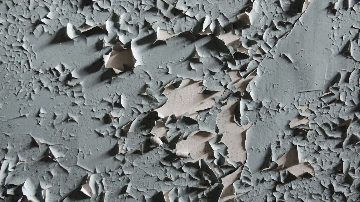 Detailed texture of cracked and peeling paint on an aged wall surface.
