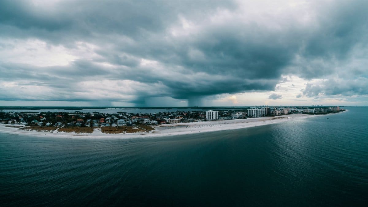 Aerial shot of a beachfront city with dramatic clouds over the ocean. Perfect for travel and nature themes.