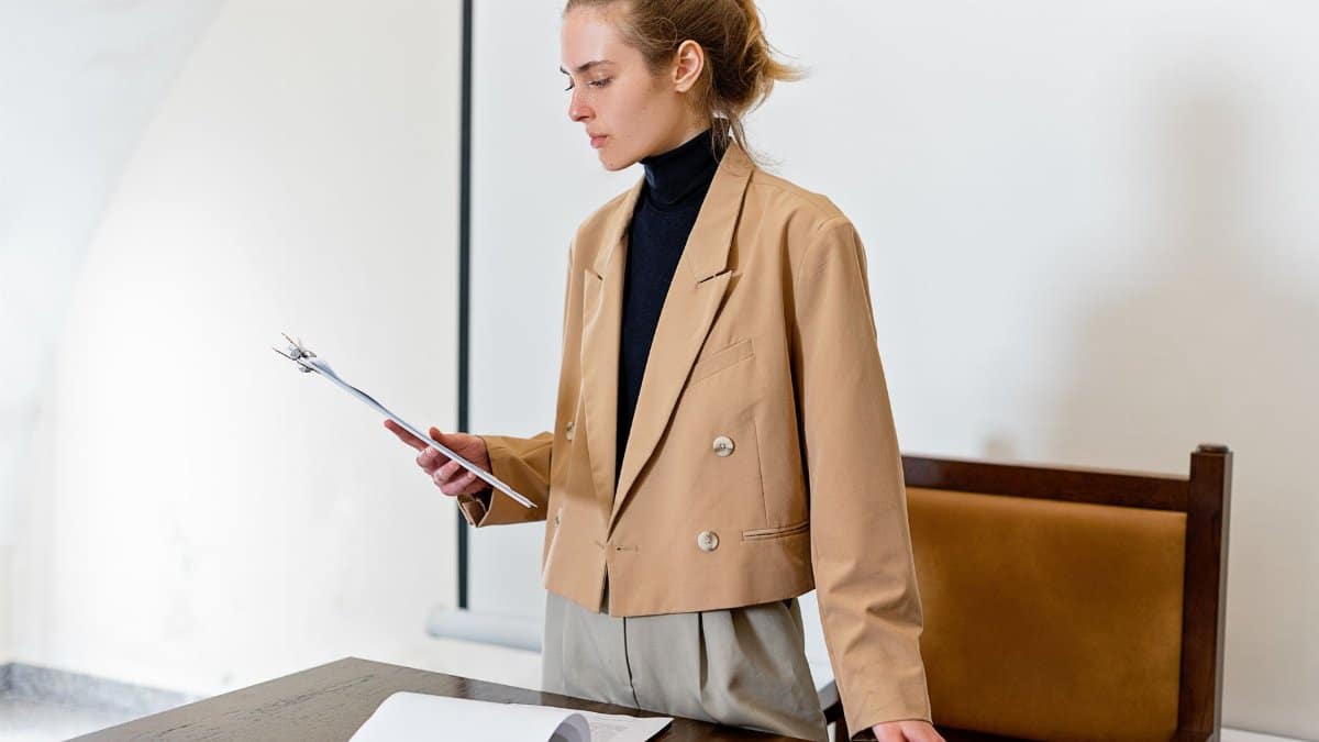 Caucasian woman in business attire evaluating a document in an indoor office setting.
