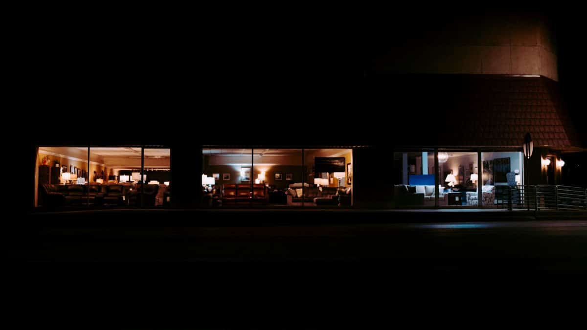A cozy view of an illuminated furniture store showcasing sofas and displays at night.