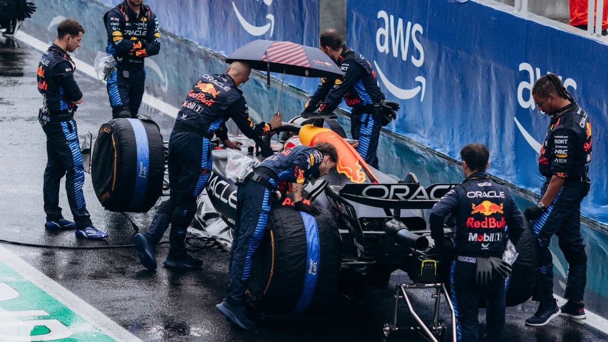 Team working on a Formula 1 car during a wet race pit stop, showcasing teamwork and precision.