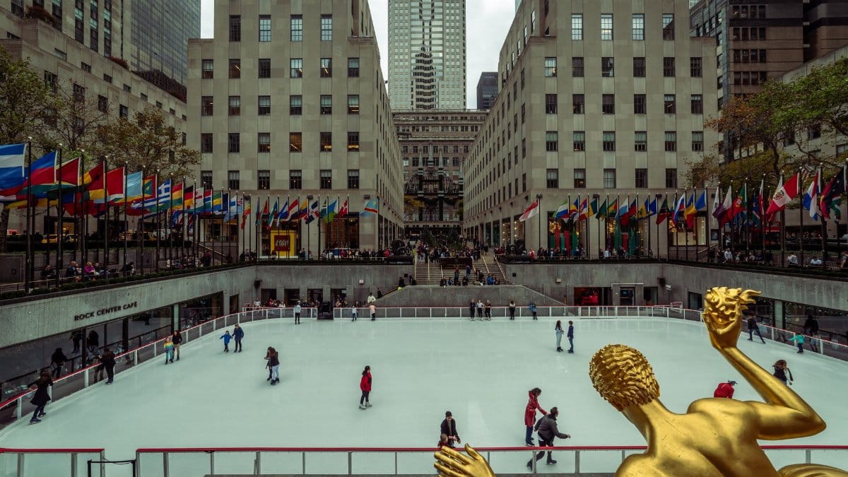 Iconic view of ice skaters at Rockefeller Center, New York City, featuring the famous Prometheus statue.