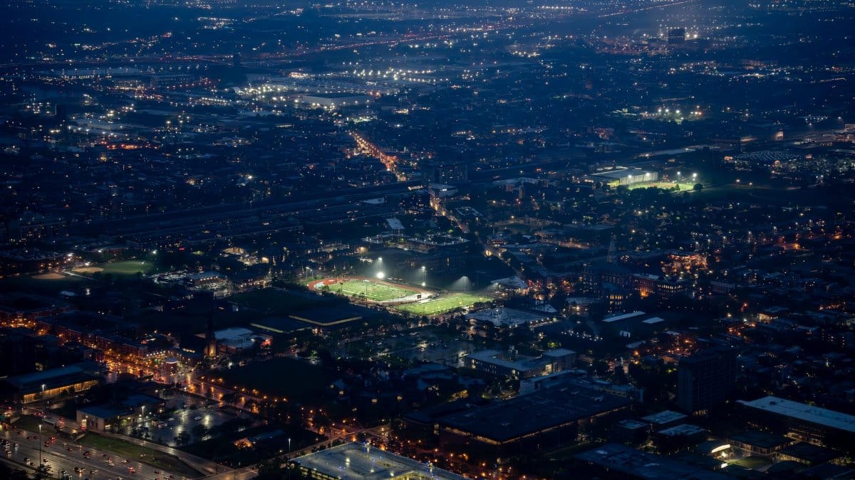 Aerial night view of a vast city with illuminated streets, highlighting urban life.