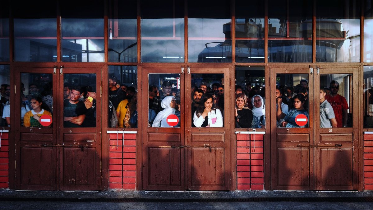 A bustling scene of people waiting inside a terminal entrance in İstanbul, Turkey.