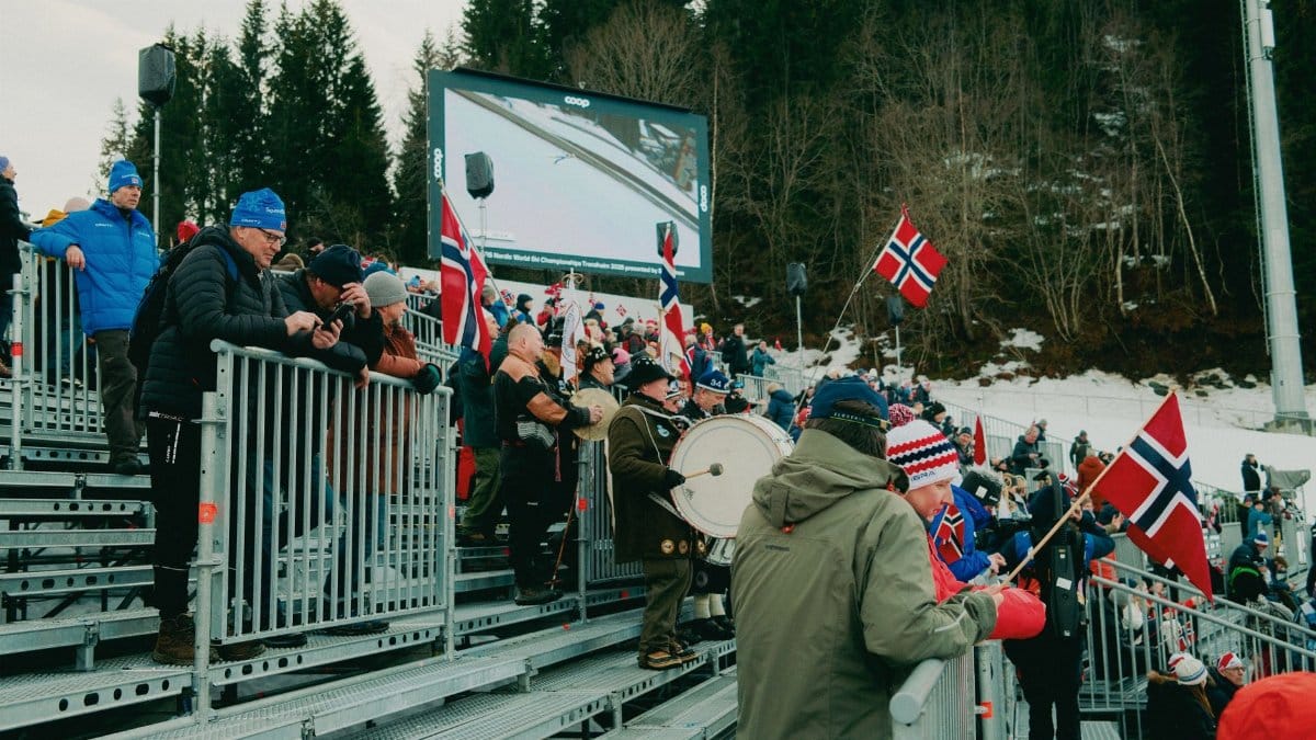 A lively crowd with flags at a winter sports event in Norway, showcasing national pride.