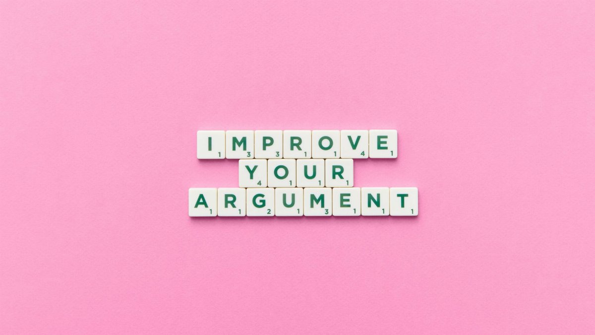 Scrabble tile letters spelling 'Improve Your Argument' on a pink background.