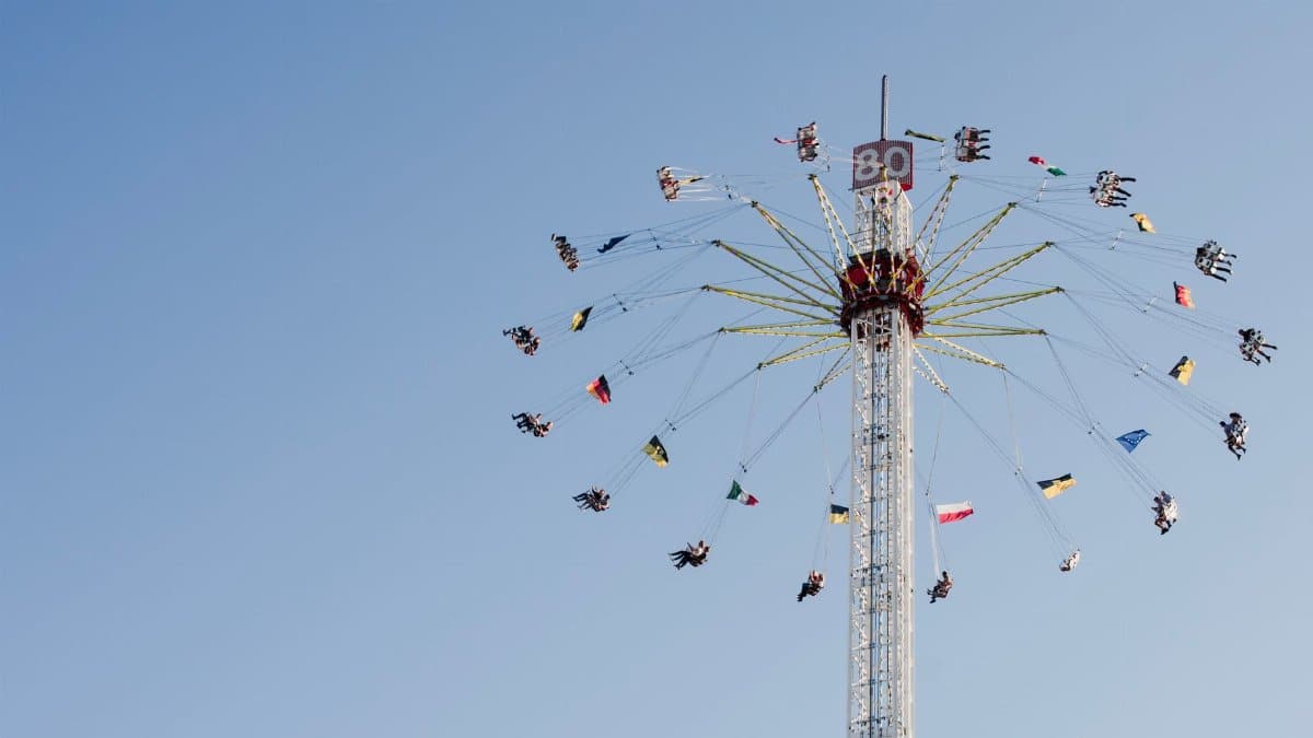 Exciting carousel ride in Stuttgart fairground against a clear blue sky, featuring colorful flags.