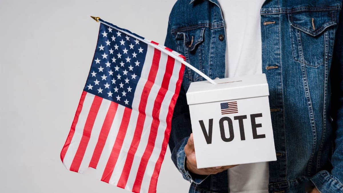Man holding an American flag and a vote box symbolizing democratic participation.