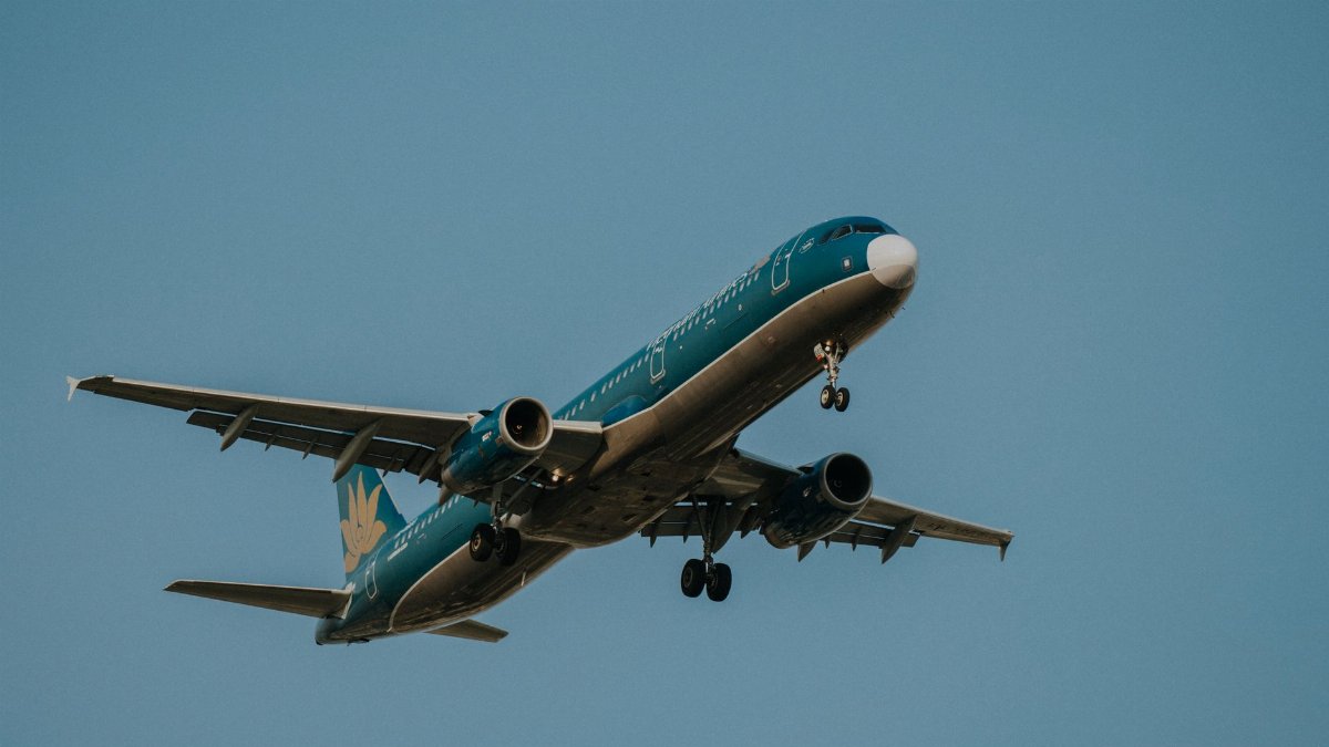 A Vietnam Airlines jet in mid-flight against a clear blue sky, showcasing aviation elegance.