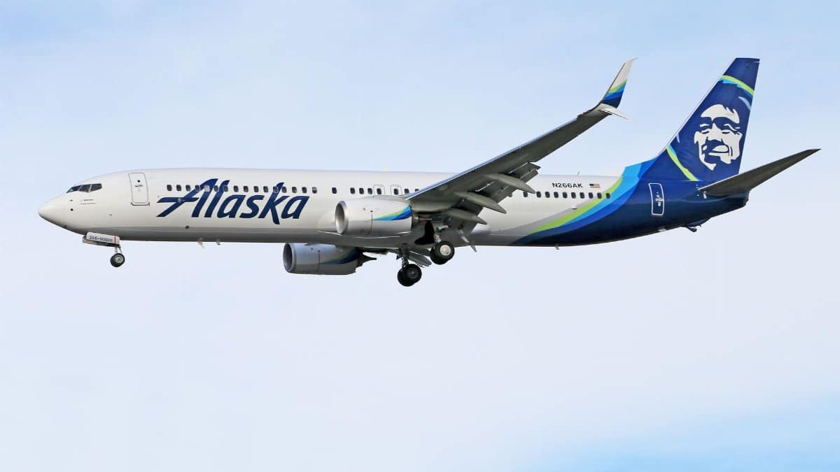 Alaska Airlines aircraft flying against a clear sky, displaying aviation and travel concepts.