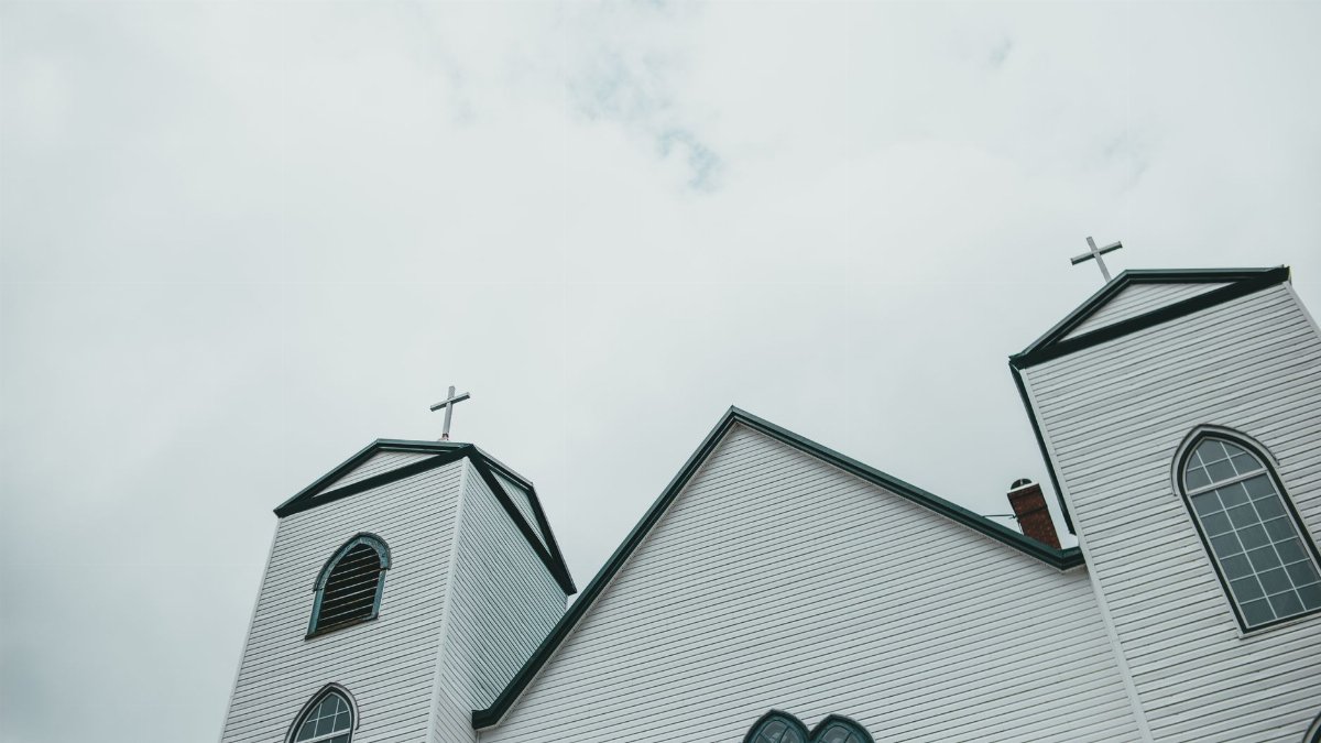 Low angle view of a church facade with crosses, set against a cloudy sky.