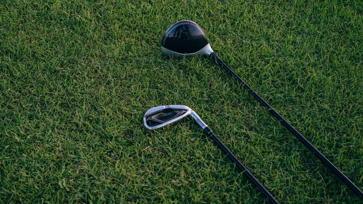 A close-up view of two golf clubs resting on neatly manicured grass, perfect for golf enthusiasts.