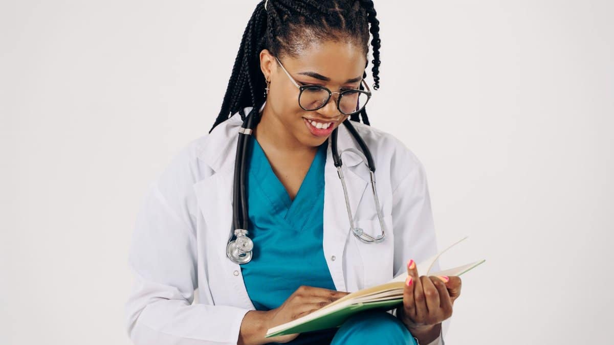Smiling female doctor with stethoscope reading medical documents.