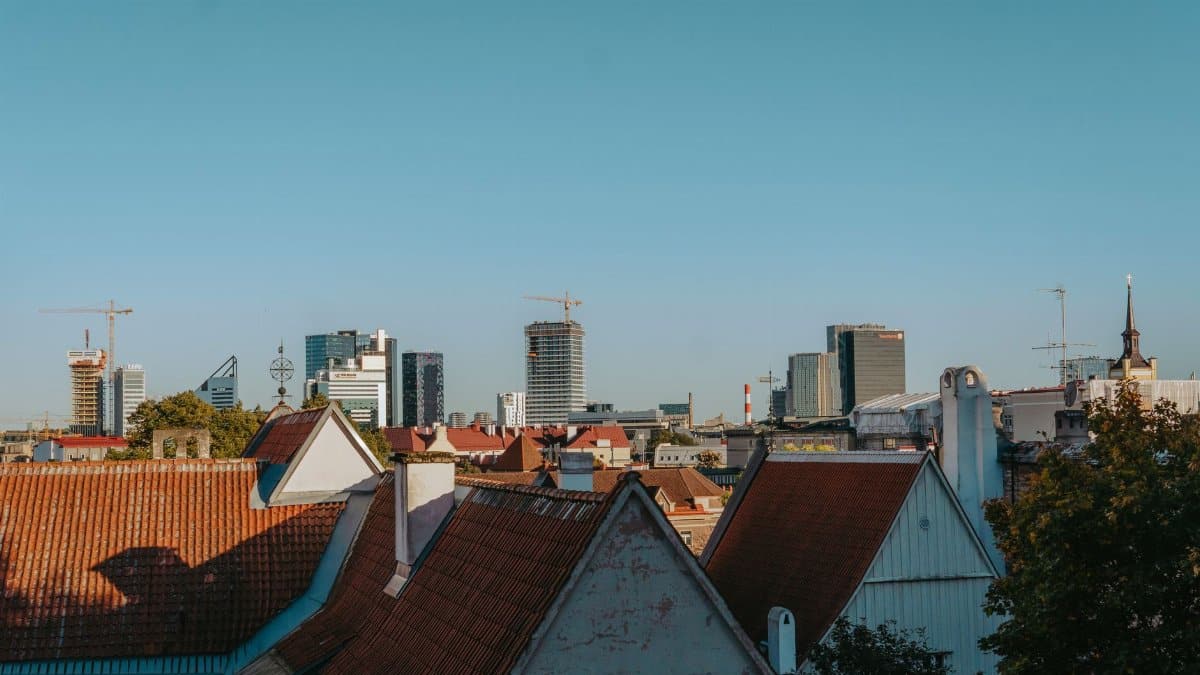 View of Tallinn's skyline blending historic red rooftops with modern skyscrapers under clear blue sky.
