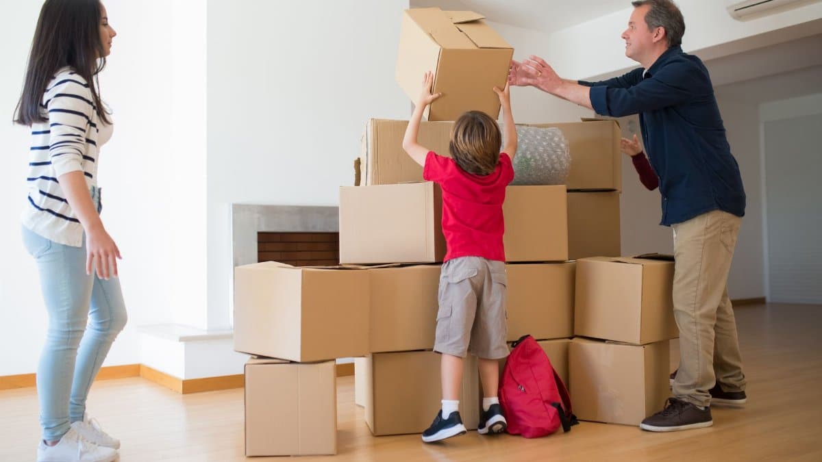 A family working together to move cardboard boxes inside their new home.