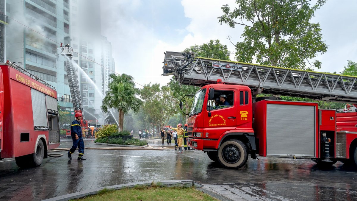 Firefighters and trucks responding to an urban building fire scene.