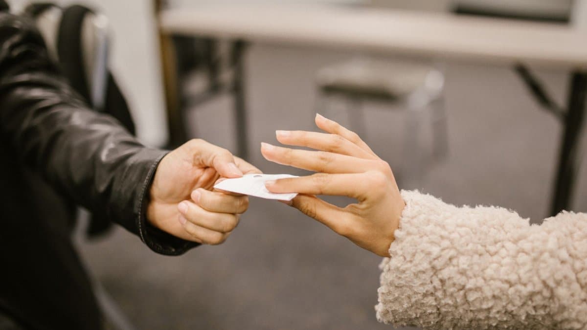 Close-up of two people exchanging a note, hinting at secretive communication.