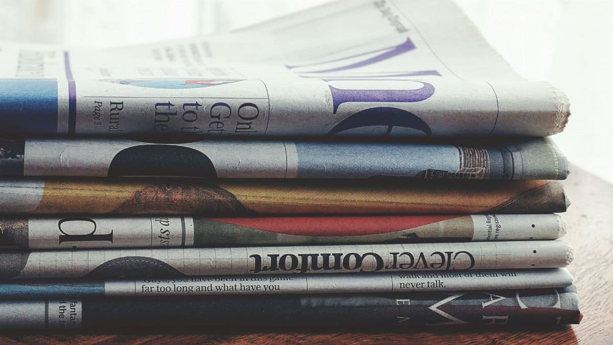 A stack of folded newspapers placed on a wooden table, symbolizing news and information.