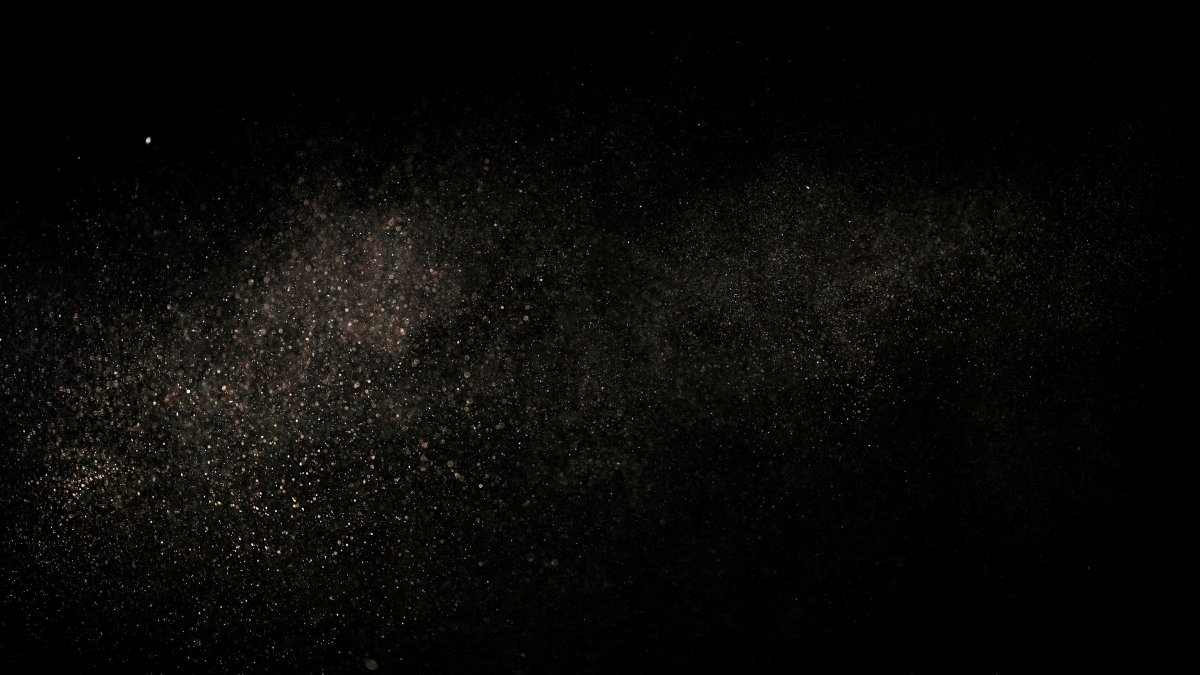 Fine dust particles suspended in air against a black backdrop, creating an abstract cosmic effect.