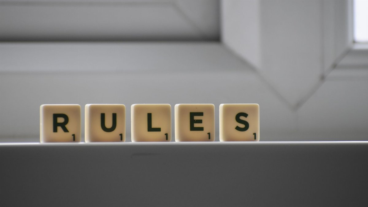 Identical small square shaped cubes with RULES title and numbers on white windowsill near window in house in daylight
