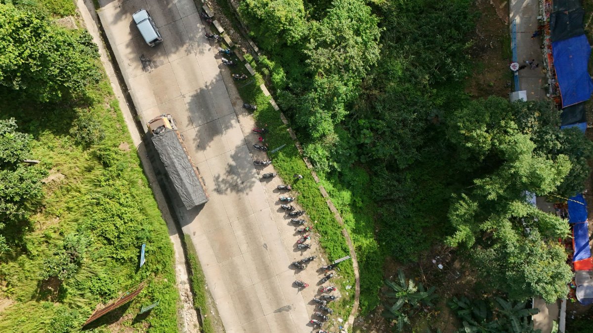 Aerial shot of a road with parked vehicles surrounded by lush greenery, creating a serene landscape.