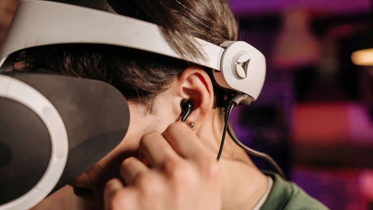 Close-up of a person wearing virtual reality headset and earphones indoors.