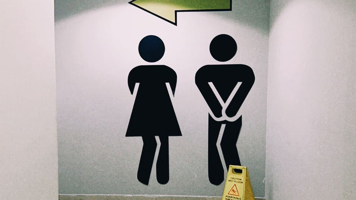 Modern restroom direction signage inside a mall in Almaty, Kazakhstan with wet floor caution sign.