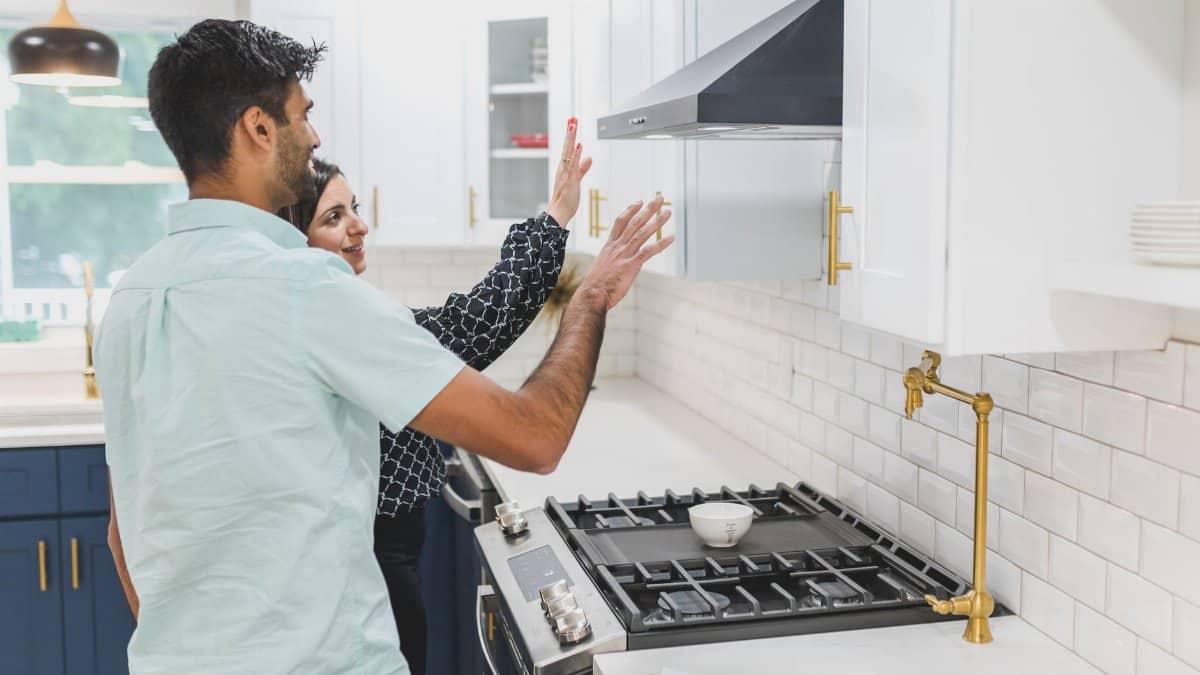 A real estate agent demonstrates kitchen features in a modern home. Ideal for real estate and lifestyle concepts.