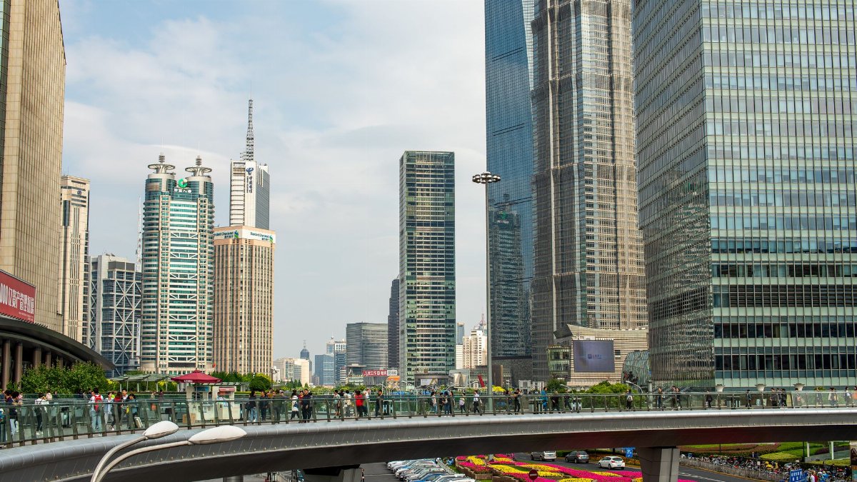 A vibrant cityscape of Shanghai featuring skyscrapers and a bustling elevated walkway.