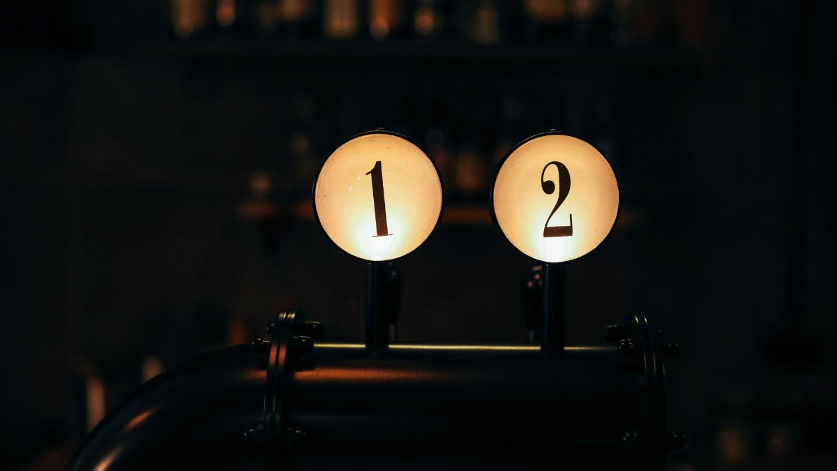 Close-up of numbered bar tap handles in a dimly lit vintage-style bar setting.