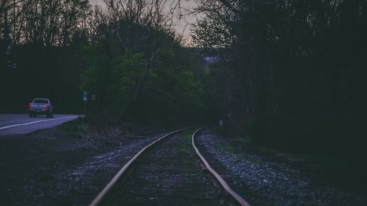 Tranquil scene of train tracks and car on a road in Long Pond, PA at twilight.