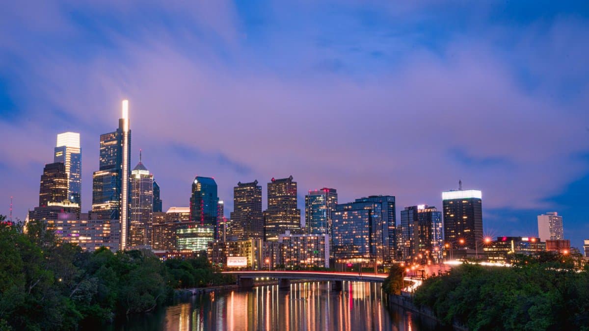 Gorgeous view of the Philadelphia skyline against a vibrant evening sky, reflected on the river.