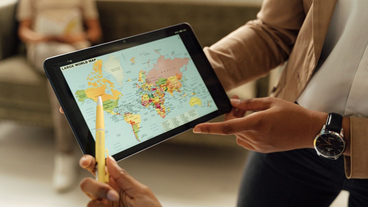 Close-up of hands holding a digital tablet displaying a world map, ideal for educational content.