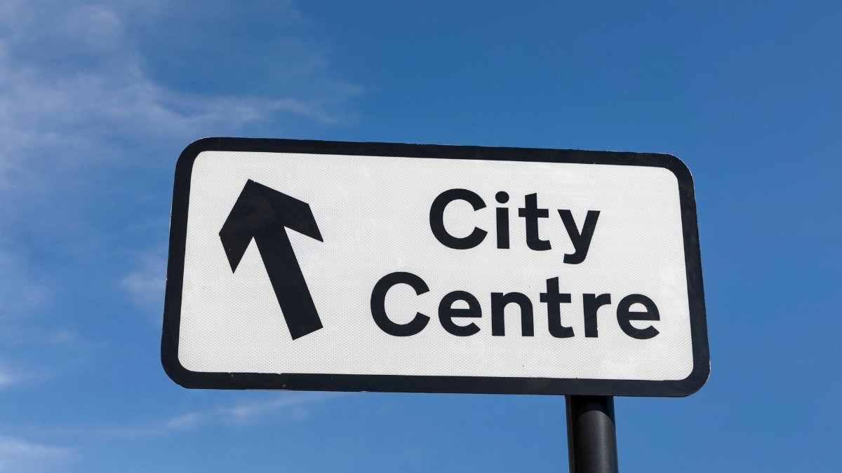 A directional sign pointing towards the city centre under a clear blue sky.