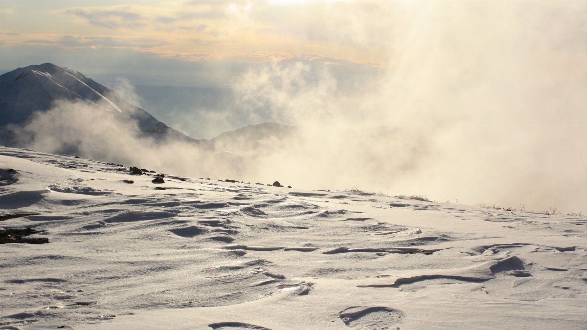 Captivating winter mountain view with fog and snow at sunrise.