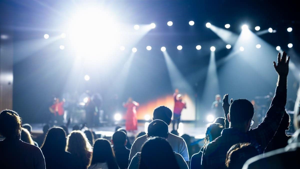 Energetic concert crowd with bright stage lights, capturing a lively atmosphere.