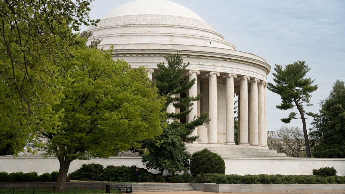 A view of the Jefferson Memorial through lush trees in Washington, D.C., showcasing classic architecture.