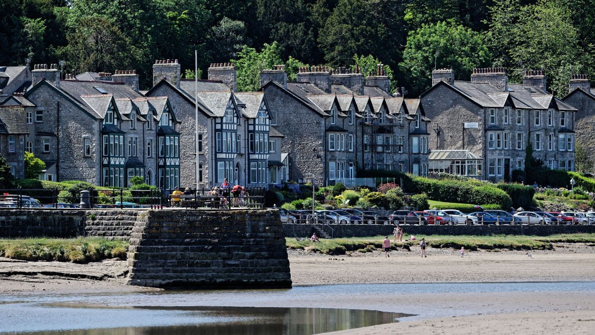 Picturesque view of traditional houses along the promenade in Arnside, with beach and estuary in the foreground.