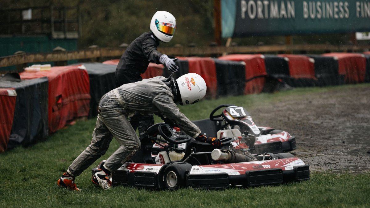Intense go-kart racing scene with racers navigating a wet track, showcasing excitement and competition.
