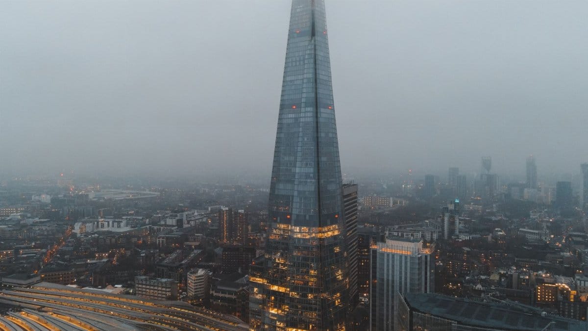 Aerial view of London city located in England with modern buildings and Shard skyscraper near railroads under gray cloudy sky in hazy day in daytime