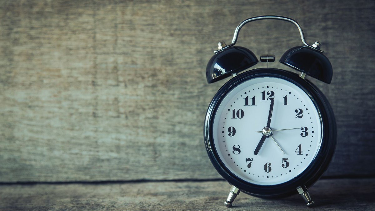 Classic black analog alarm clock on rustic wooden background, perfect for time and nostalgia themes.