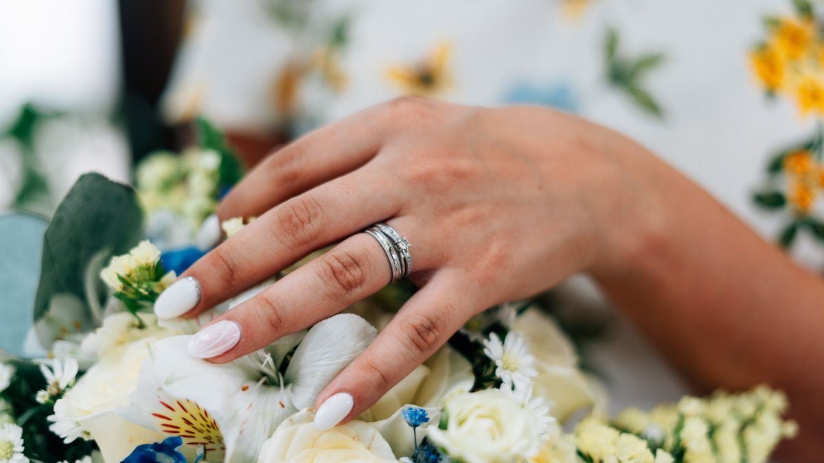 Close-up of a bride's hand with a wedding ring, beautifully set against a vibrant floral bouquet.