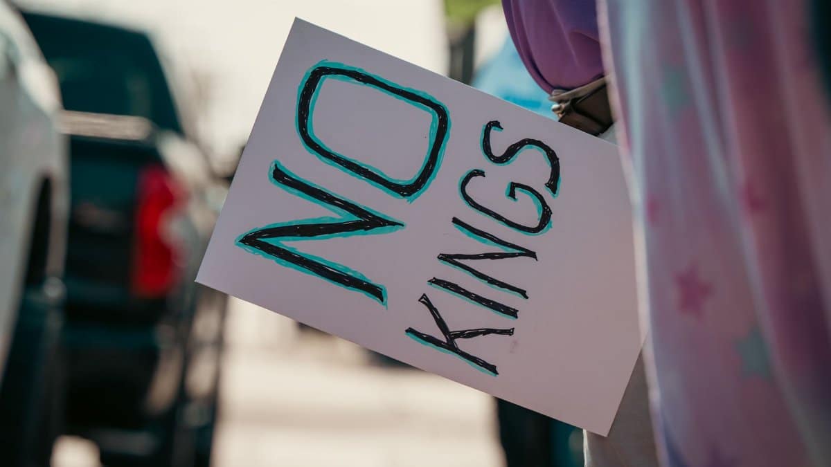 Protester holds a sign with 'No Kings' message during street demonstration.